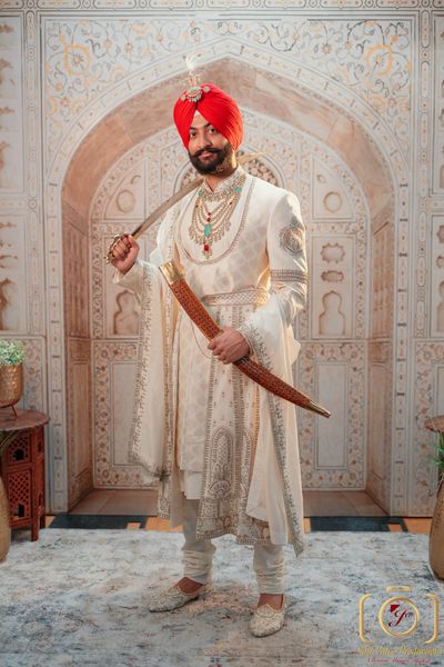 Punjabi groom portrait — red turban, cream sherwani and kirpan